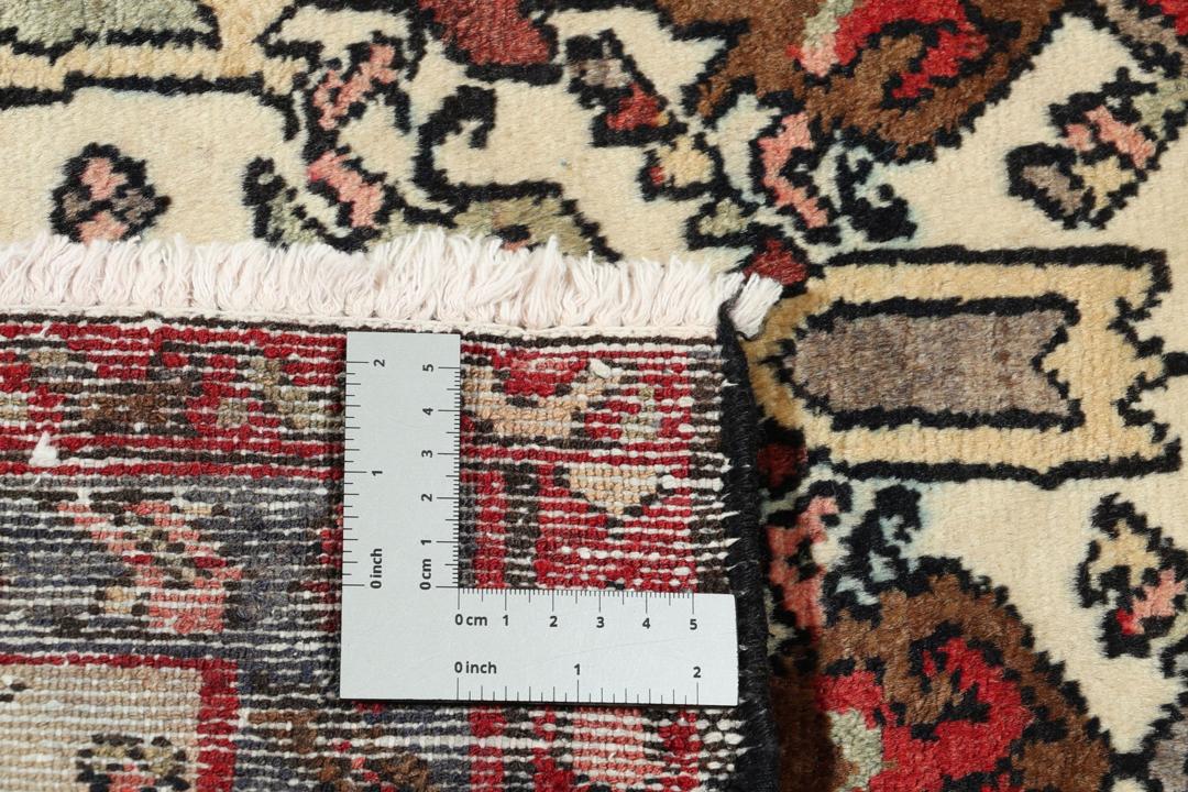 Et håndknyttet Hamadan-tæppe fra Mellemøsten med et levende blomstermønster på en beige bund.