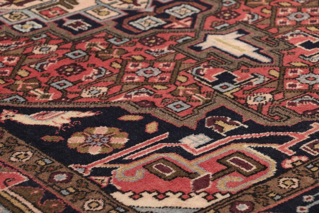 Een handgeknoopt Koliai vloerkleed uit het Midden-Oosten met een donkerrood veld en tribale geometrische patronen.