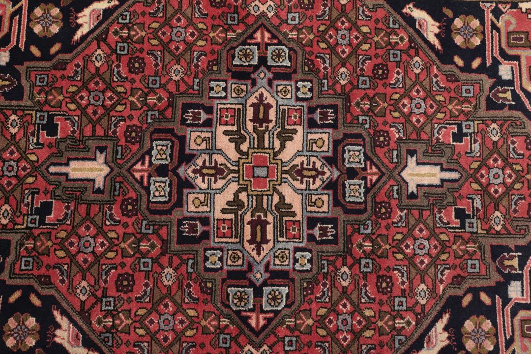Een handgeknoopt Koliai vloerkleed uit het Midden-Oosten met een donkerrood veld en tribale geometrische patronen.