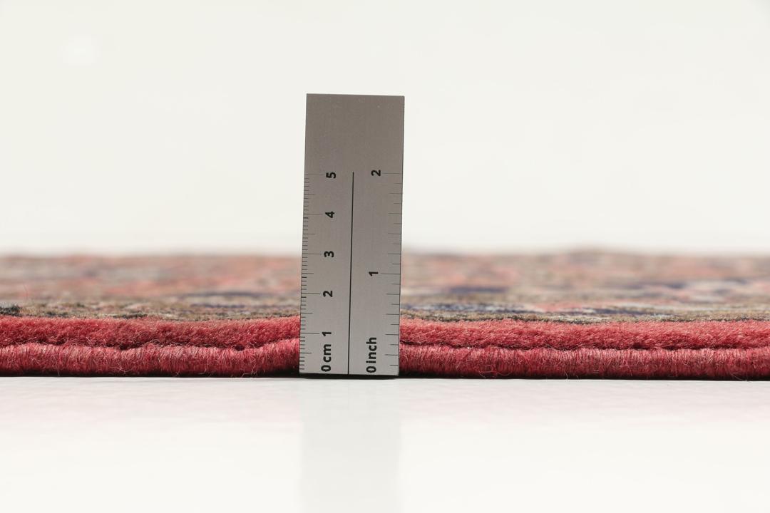 Een handgeknoopt Koliai vloerkleed uit het Midden-Oosten met een donkerrood veld en tribale geometrische patronen.
