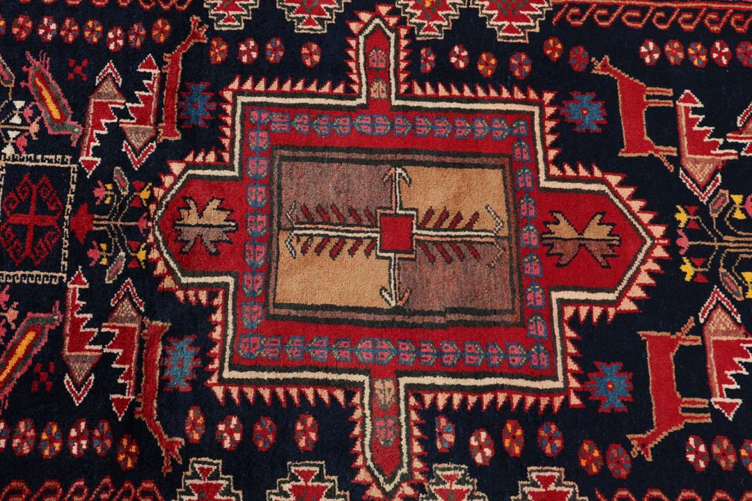 Håndknyttet uldtæppe fra Mellemøsten i mørkeblå og røde nuancer med traditionelle motiver