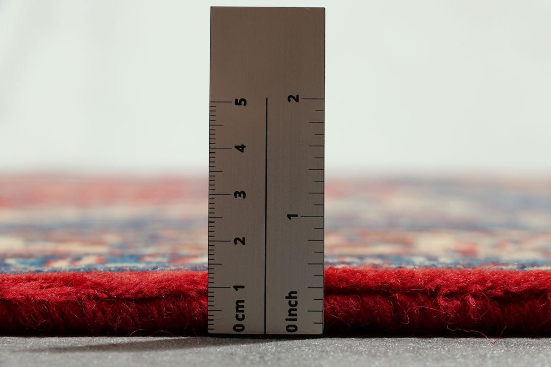 Een handgeknoopt Mahal-vloerkleed uit het Midden-Oosten met een levendig rood en blauw bloemenpatroon.
