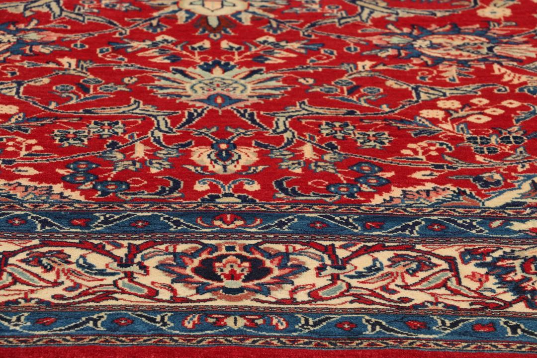 Een handgeknoopt Mahal-vloerkleed uit het Midden-Oosten met een levendig rood en blauw bloemenpatroon.