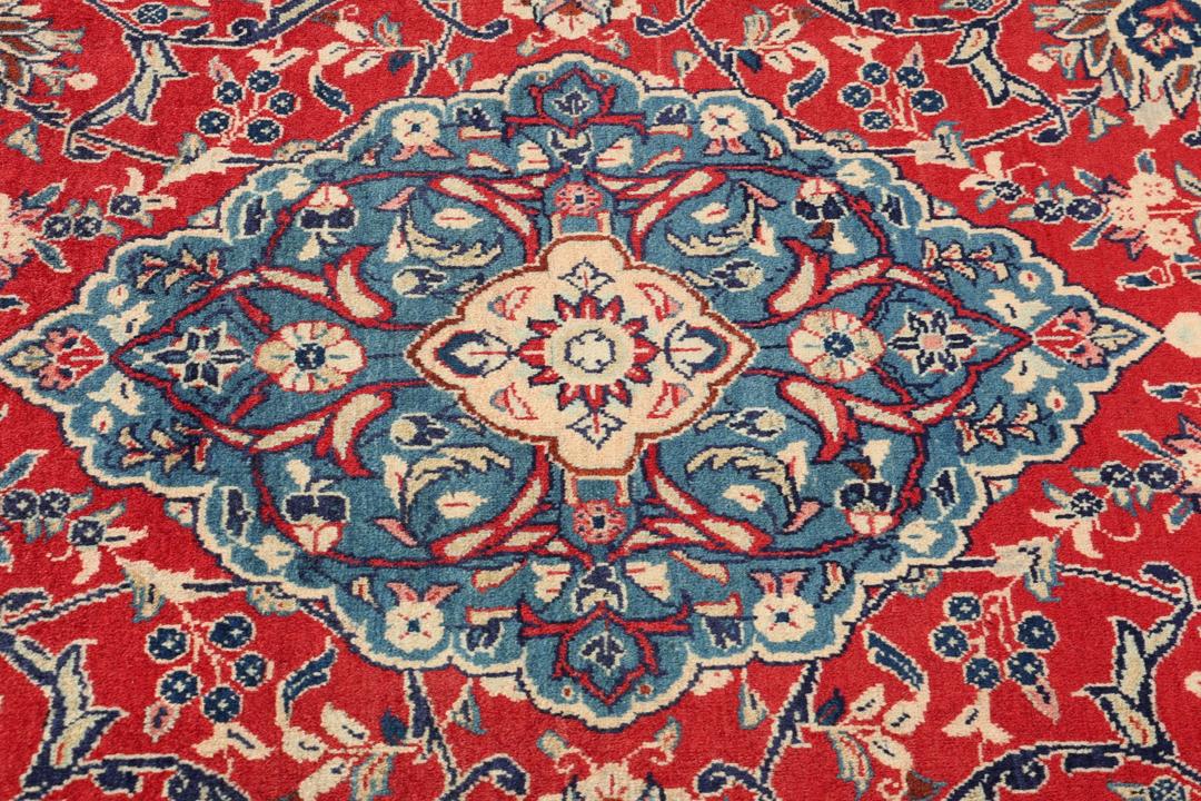 Een handgeknoopt Mahal-vloerkleed uit het Midden-Oosten met een levendig rood en blauw bloemenpatroon.