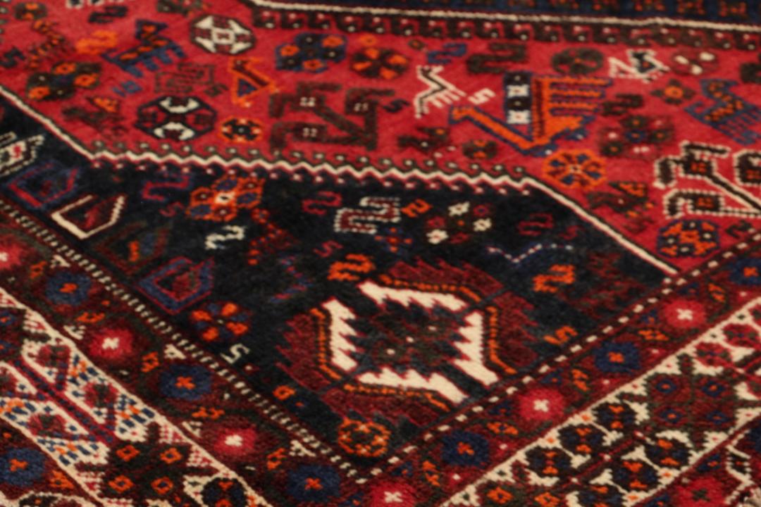 Handgeknoopt Shiraz-tapijt uit het Midden-Oosten met een levendig rood en blauw geometrisch ontwerp.