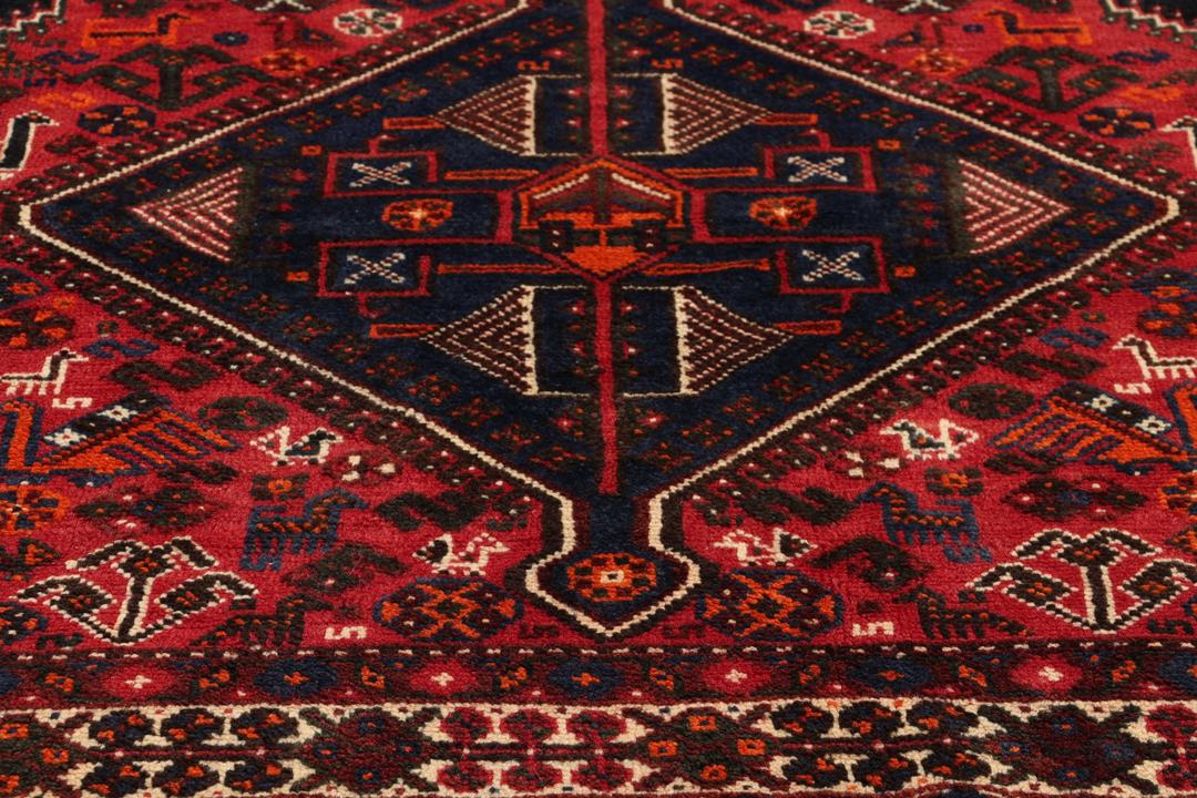 Handgeknoopt Shiraz-tapijt uit het Midden-Oosten met een levendig rood en blauw geometrisch ontwerp.