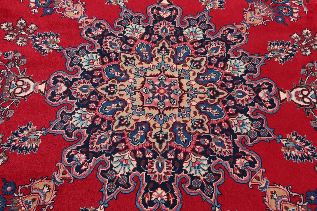 Un tapis Mashad noué à la main avec un médaillon central sur fond rouge provenant du Moyen-Orient