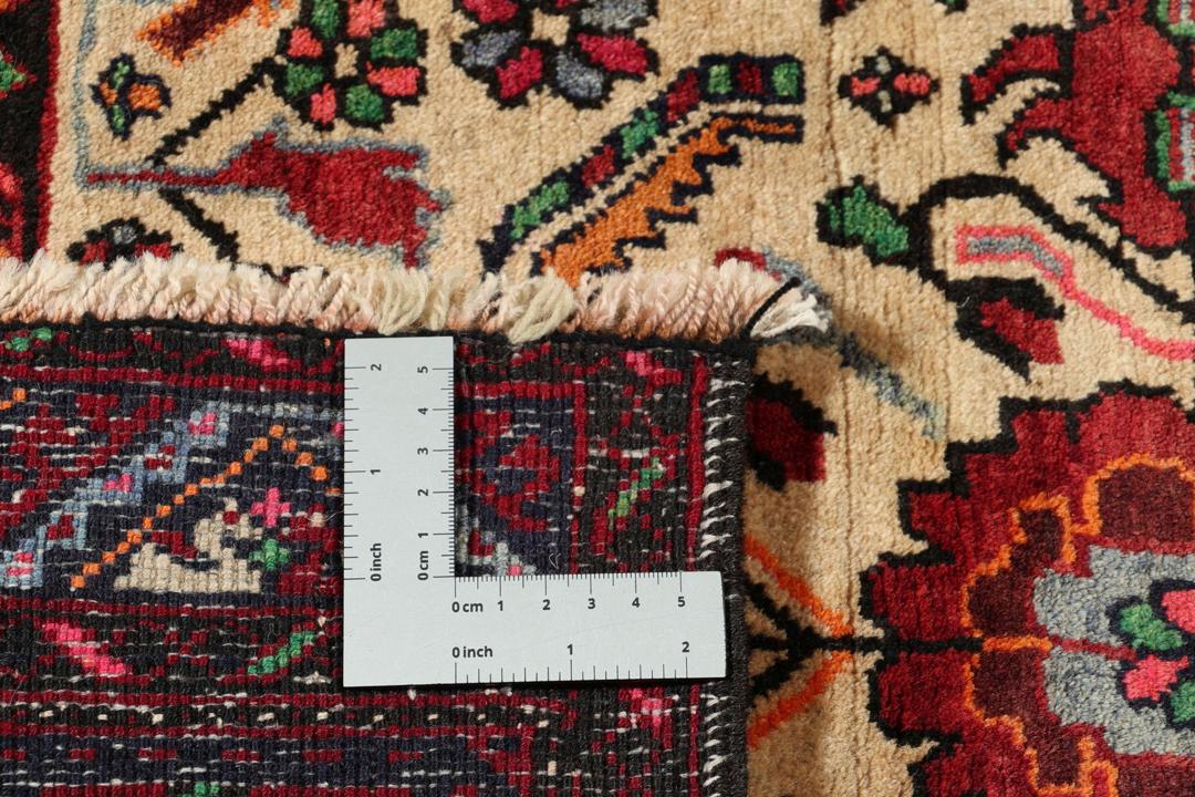 A hand-knotted Baluch rug from the Middle East featuring red and beige floral patterns.