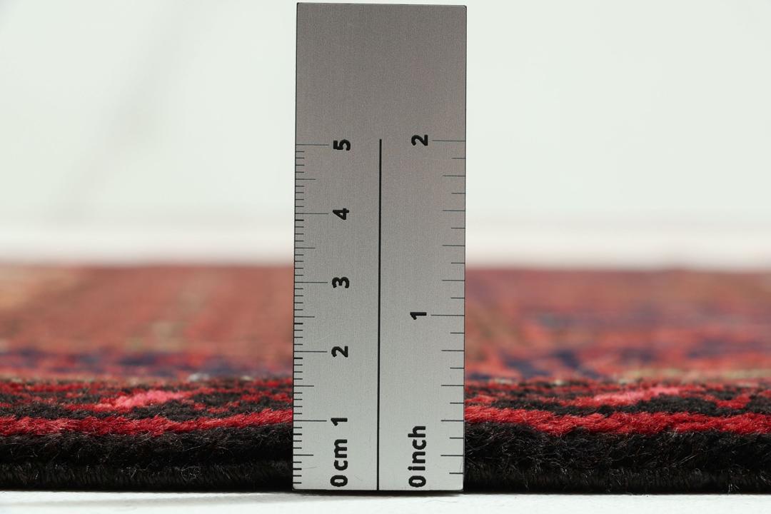 A hand-knotted Baluch rug from the Middle East featuring red and beige floral patterns.