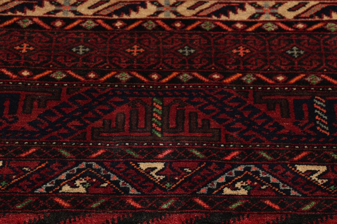 A hand-knotted Baluch rug from the Middle East featuring red and beige floral patterns.
