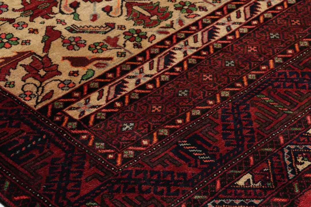 A hand-knotted Baluch rug from the Middle East featuring red and beige floral patterns.
