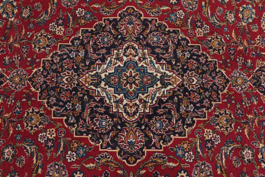 A large rectangular hand-knotted Keshan rug from the Middle East in red and dark blue.