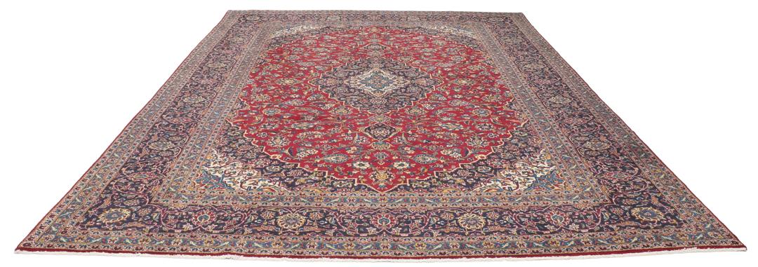 A large rectangular hand-knotted Keshan rug from the Middle East in red and dark blue.
