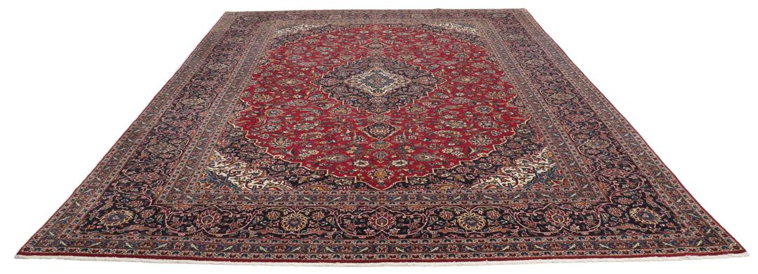 A large rectangular hand-knotted Keshan rug from the Middle East in red and dark blue.