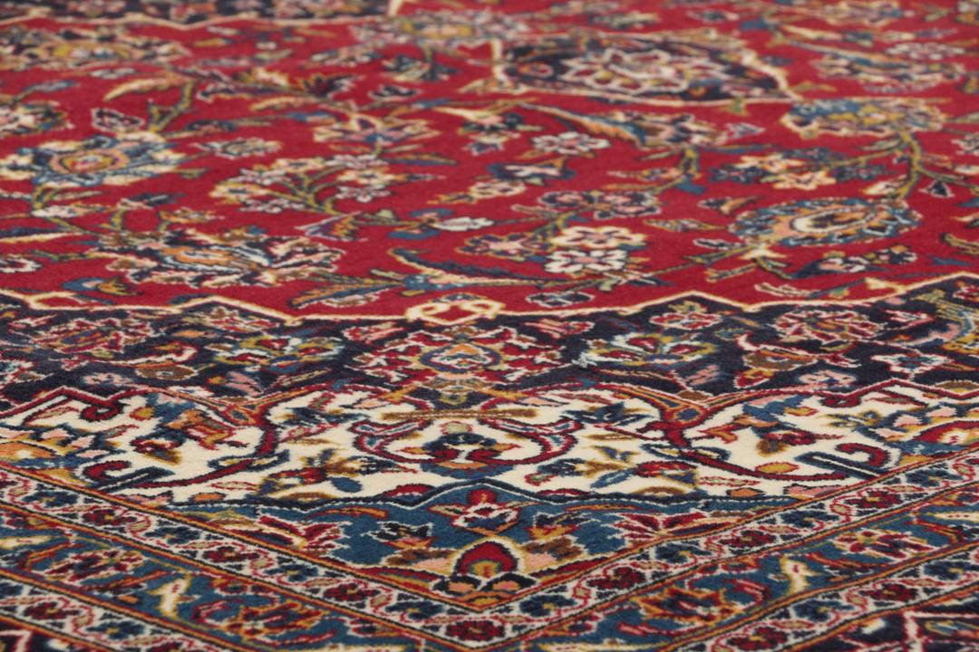 A large rectangular hand-knotted Keshan rug from the Middle East in red and dark blue.