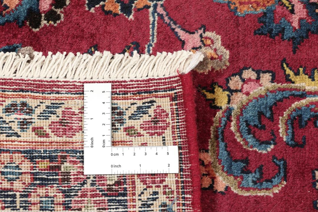 A hand-knotted Mashad rug from the Middle East in deep red and blue tones.