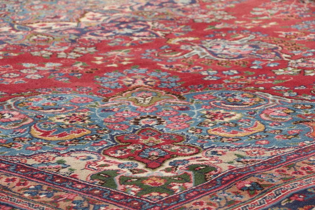 A hand-knotted Mashad rug from the Middle East in deep red and blue tones.