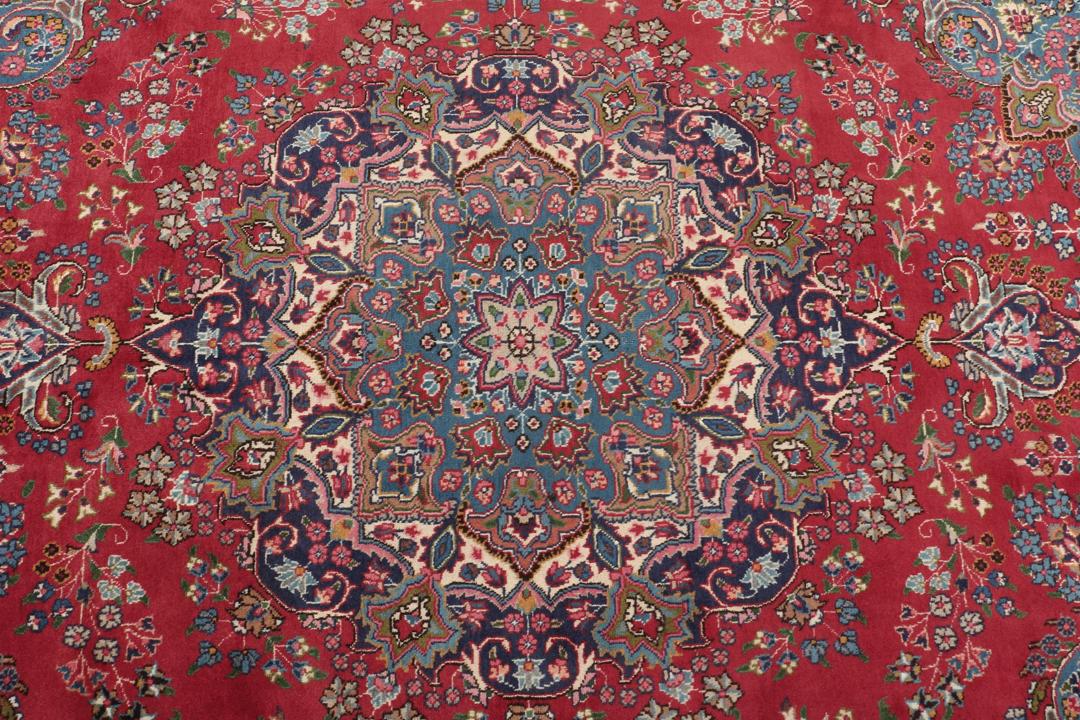 A hand-knotted Mashad rug from the Middle East in deep red and blue tones.