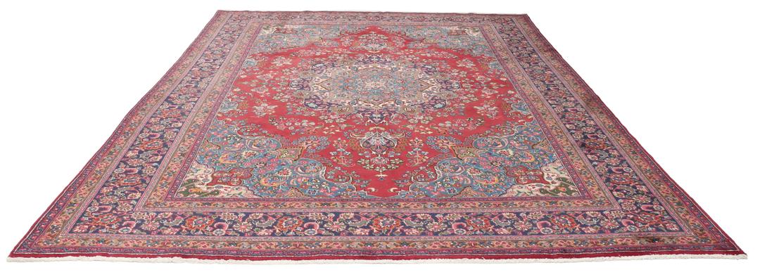 A hand-knotted Mashad rug from the Middle East in deep red and blue tones.