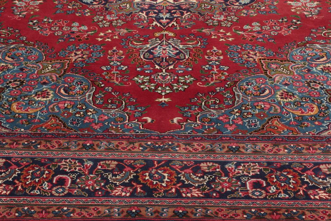 A hand-knotted Mashad rug from the Middle East in deep red and blue tones.