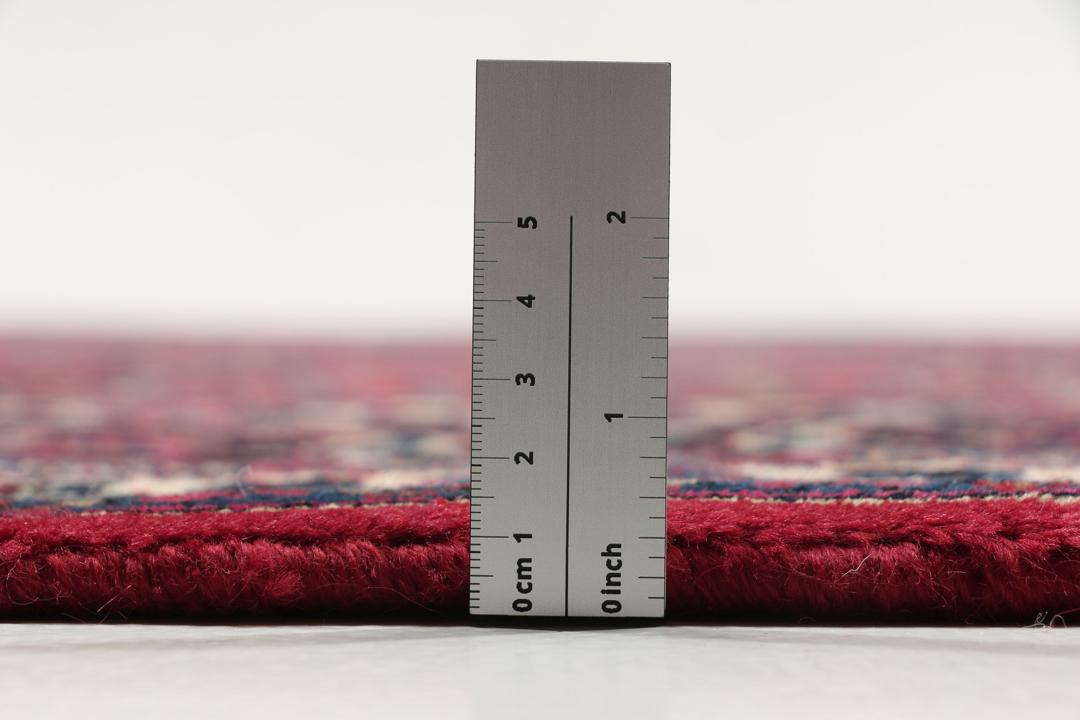 A hand-knotted Mashad rug from the Middle East in deep red and blue tones.