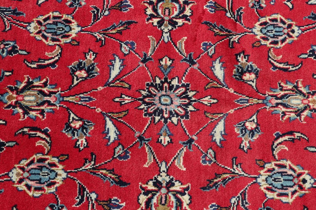 Hand-knotted Keshan rug from the Middle East featuring a vibrant red field with intricate floral patterns.