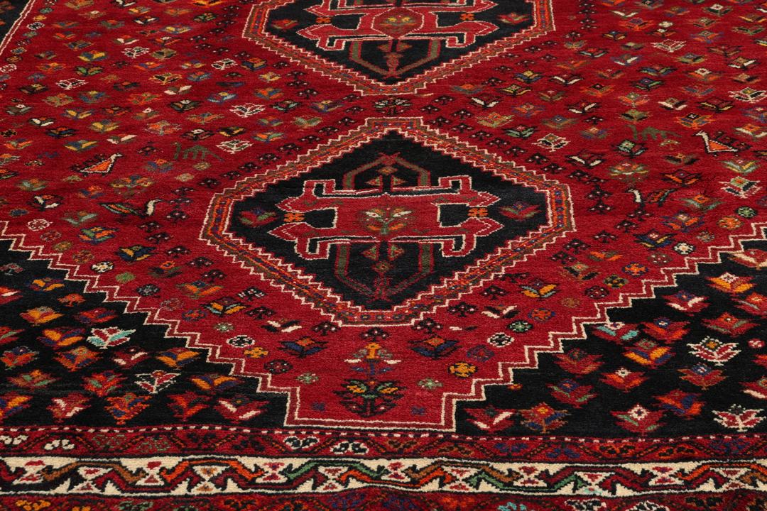 A hand-knotted Shiraz rug from the Middle East featuring a vibrant red field and geometric motifs.