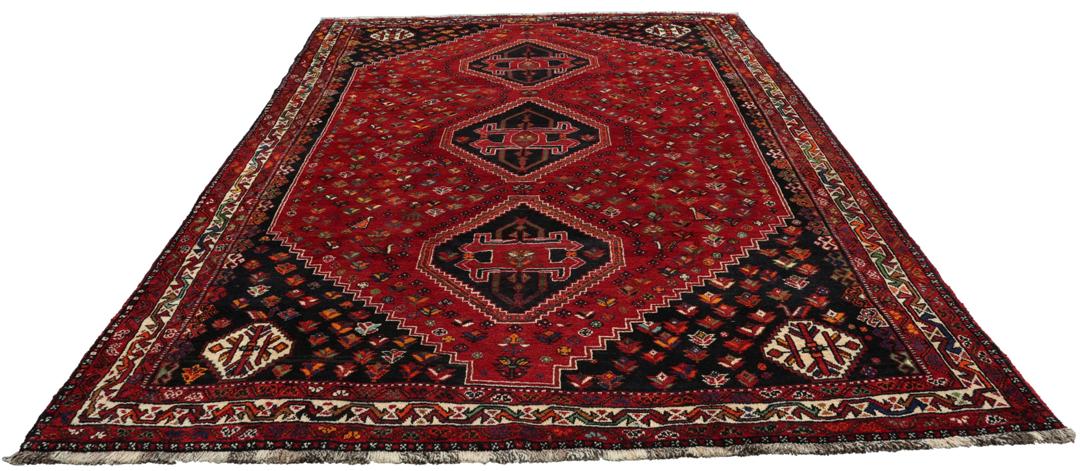 A hand-knotted Shiraz rug from the Middle East featuring a vibrant red field and geometric motifs.