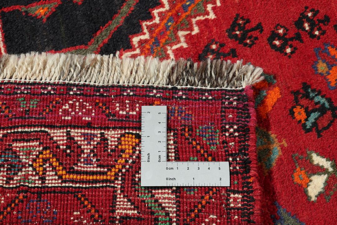 A hand-knotted Shiraz rug from the Middle East featuring a vibrant red field and geometric motifs.