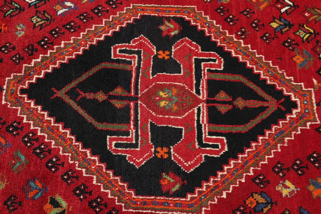 A hand-knotted Shiraz rug from the Middle East featuring a vibrant red field and geometric motifs.