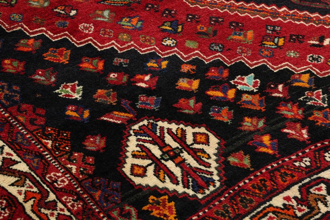 A hand-knotted Shiraz rug from the Middle East featuring a vibrant red field and geometric motifs.