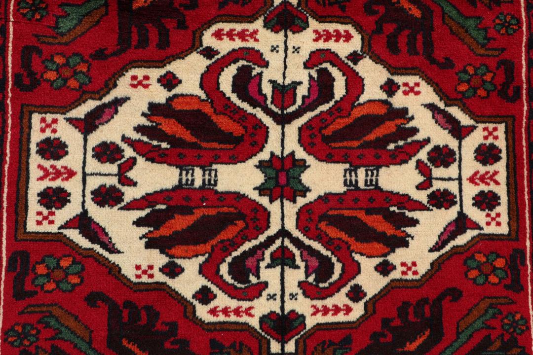 Handgeknoopt Baluch-tapijt in donkerrood met tribale medaillonmotieven uit het Midden-Oosten.