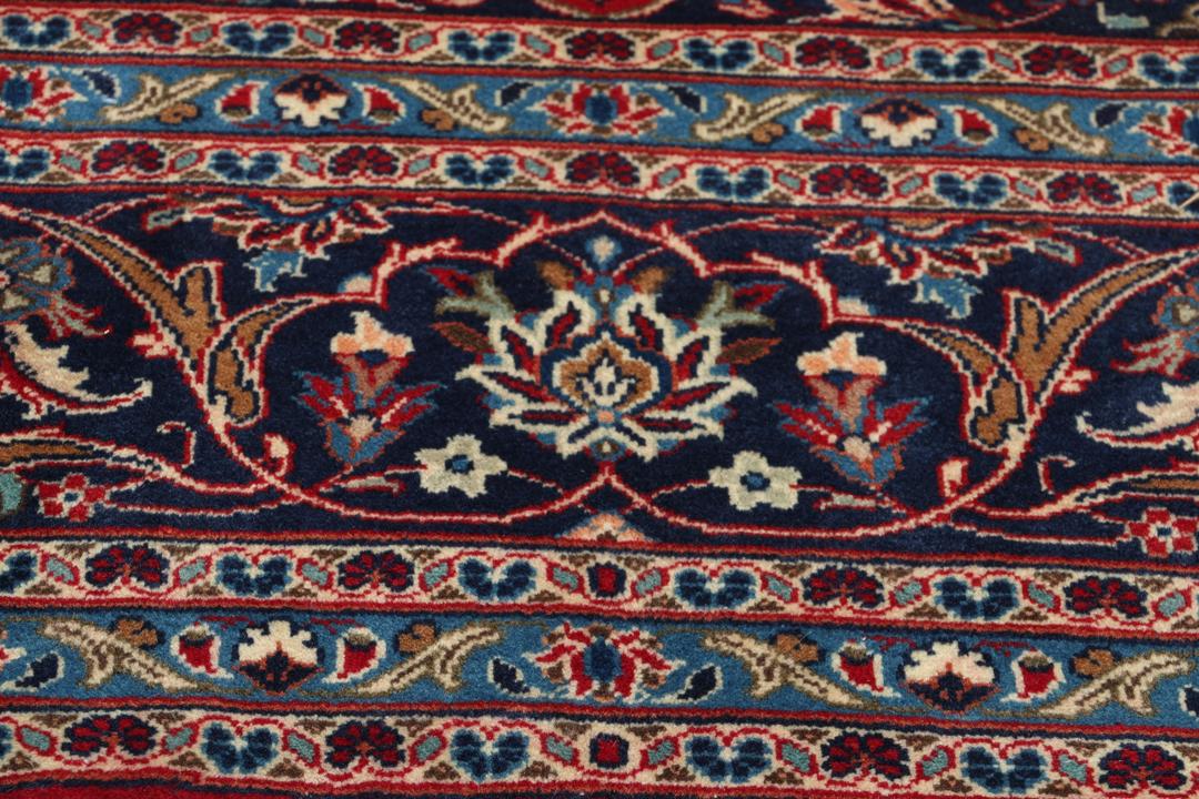 Un tapis Keshan rouge noué à la main avec un médaillon central classique et des motifs floraux.
