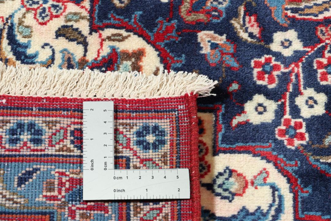 Un tapis Keshan rouge noué à la main avec un médaillon central classique et des motifs floraux.