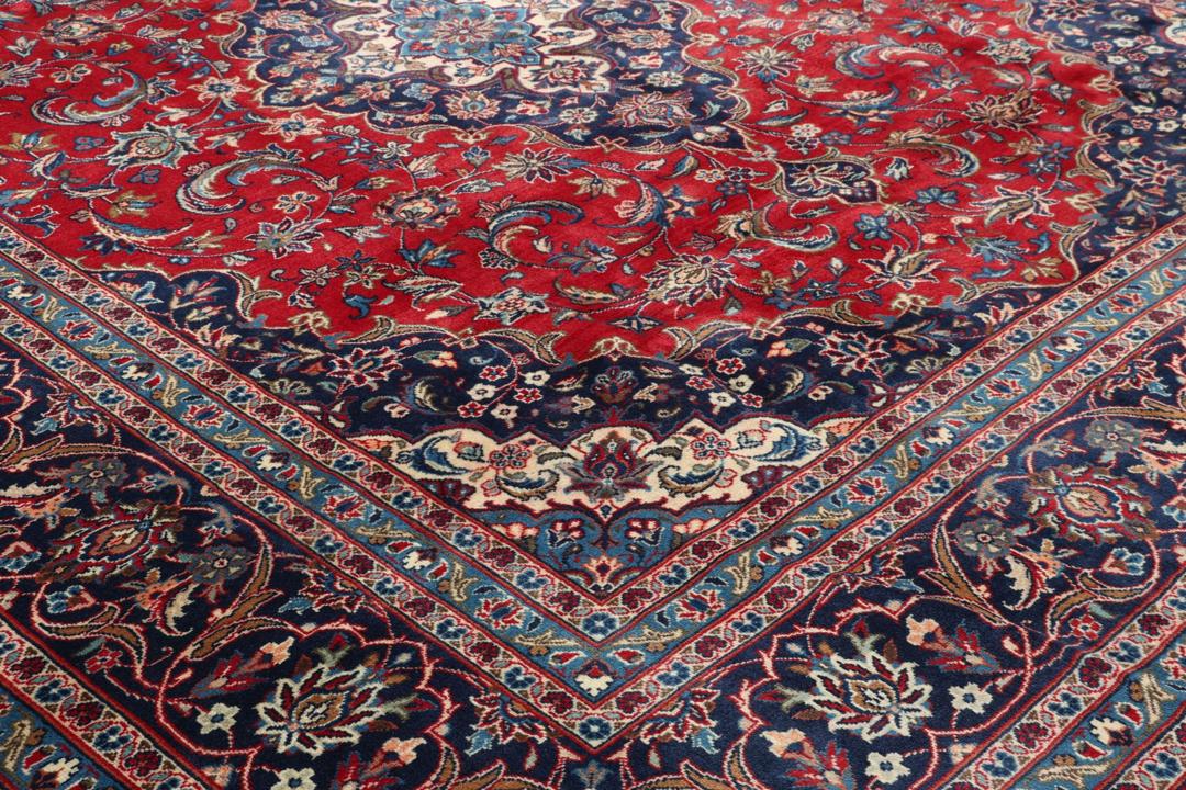 Un tapis Keshan rouge noué à la main avec un médaillon central classique et des motifs floraux.