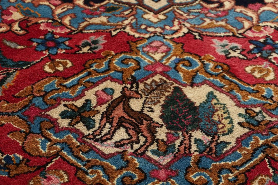 Et håndknyttet Mashad-tæppe fra Mellemøsten med et dybrødt felt og blomstermønstre.