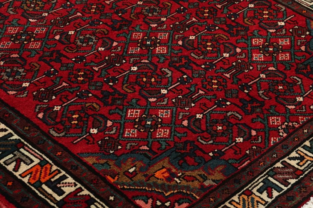 A hand-knotted Hosseinabad runner with a deep red field and geometric patterns from the Middle East.