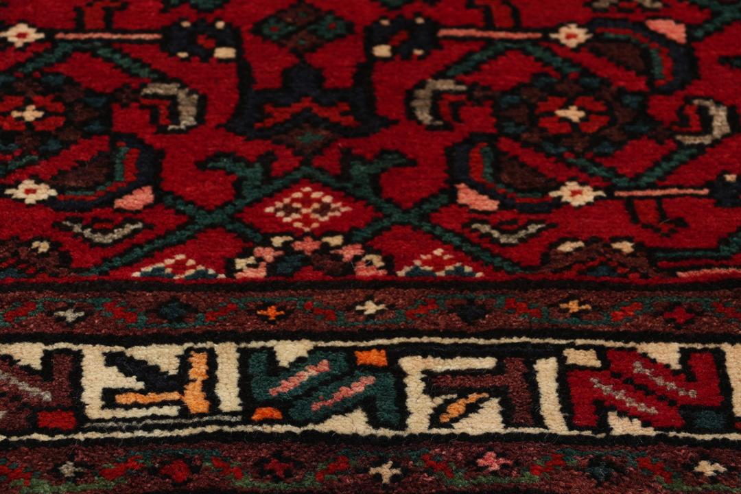 A hand-knotted Hosseinabad runner with a deep red field and geometric patterns from the Middle East.