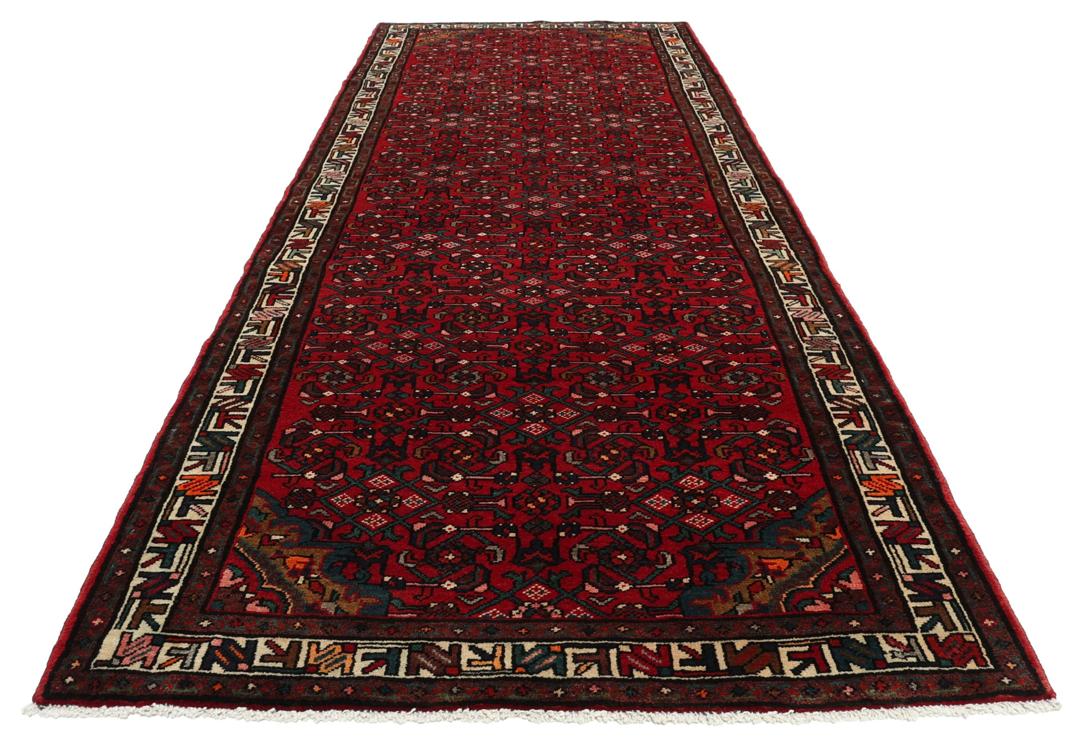 A hand-knotted Hosseinabad runner with a deep red field and geometric patterns from the Middle East.