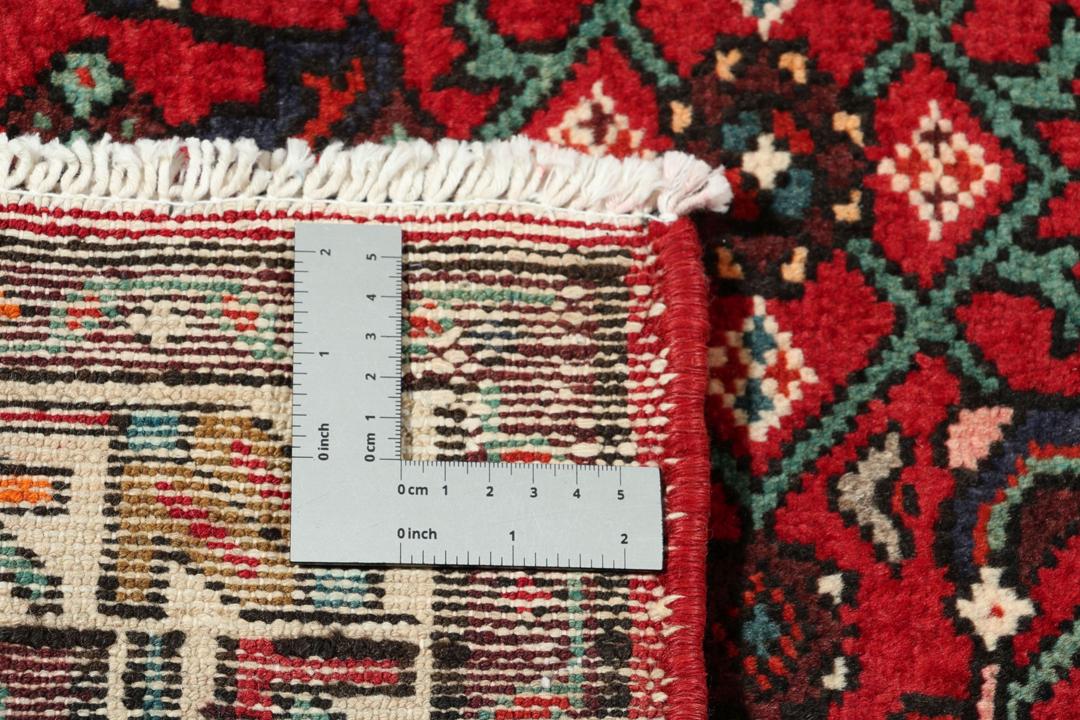 A hand-knotted Hosseinabad runner with a deep red field and geometric patterns from the Middle East.