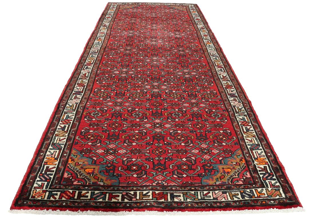 A hand-knotted Hosseinabad runner with a deep red field and geometric patterns from the Middle East.