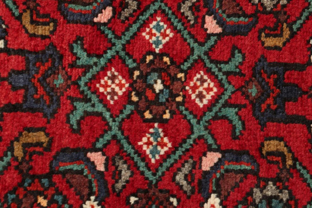 A hand-knotted Hosseinabad runner with a deep red field and geometric patterns from the Middle East.