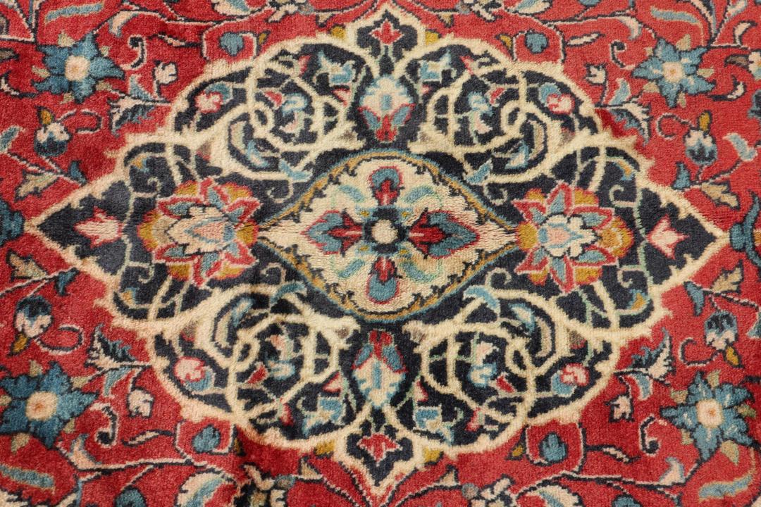 Hand-knotted Sarough rug from the Middle East with a red field and floral patterns.
