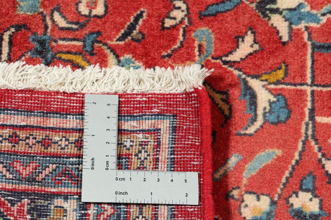 Hand-knotted Sarough rug from the Middle East with a red field and floral patterns.