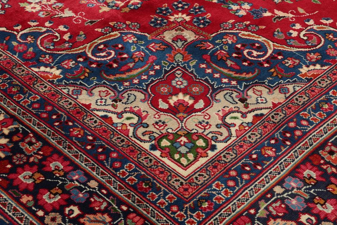 Hand-knotted Mashad rug from the Middle East with a red and blue floral pattern.
