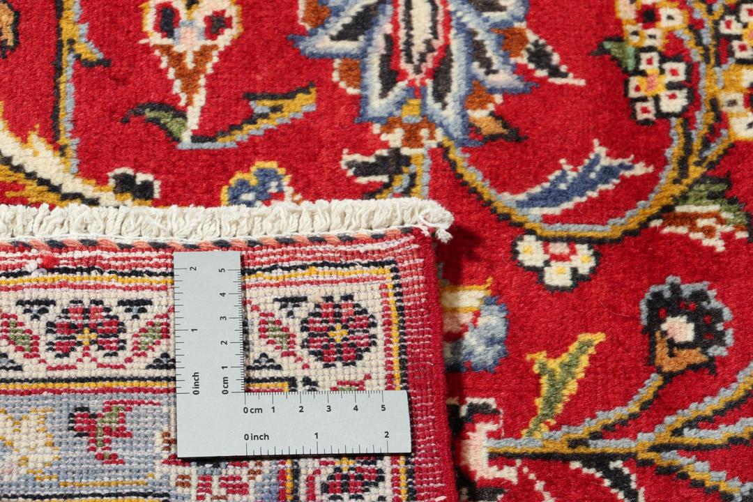 A hand-knotted Keshan rug with a red field and traditional floral medallion from the Middle East.