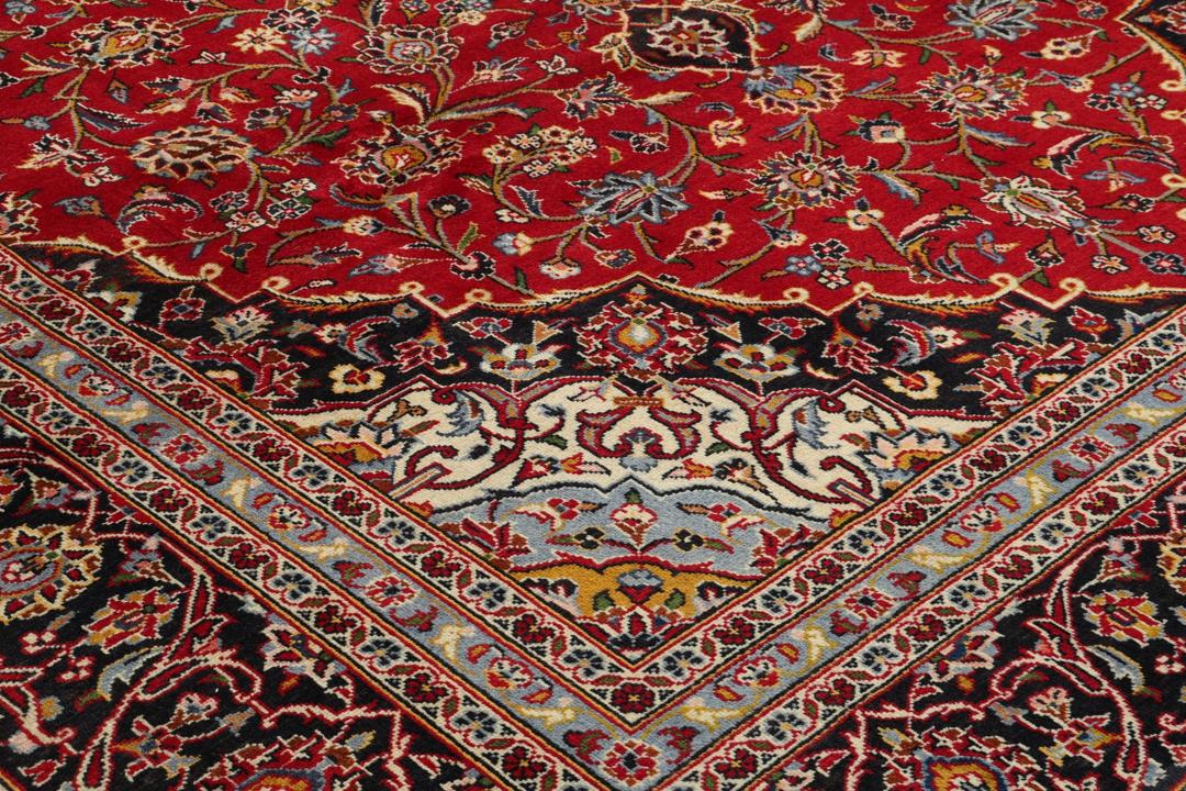 A hand-knotted Keshan rug with a red field and traditional floral medallion from the Middle East.