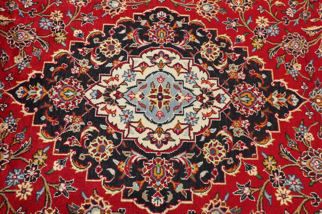 A hand-knotted Keshan rug with a red field and traditional floral medallion from the Middle East.