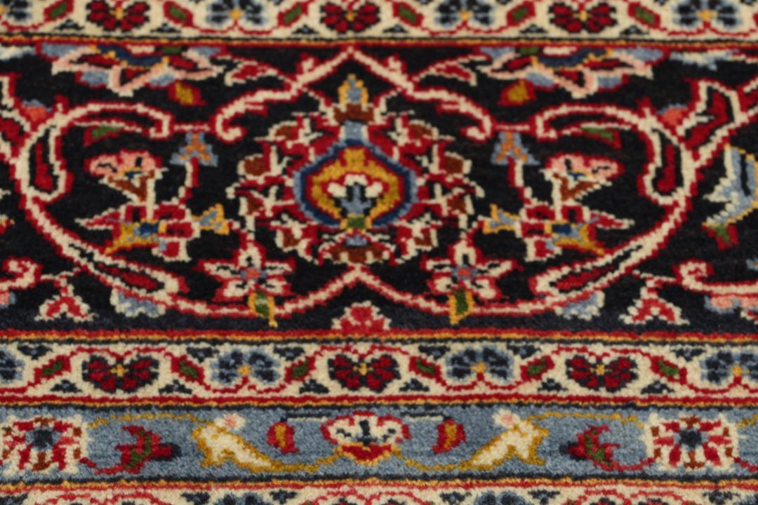 A hand-knotted Keshan rug with a red field and traditional floral medallion from the Middle East.