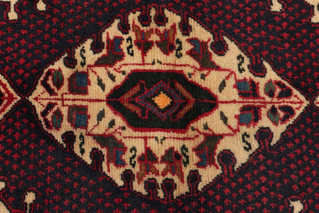 Een handgeknoopt Beluch-tapijt met donkerrode en beige tribale patronen uit het Midden-Oosten.